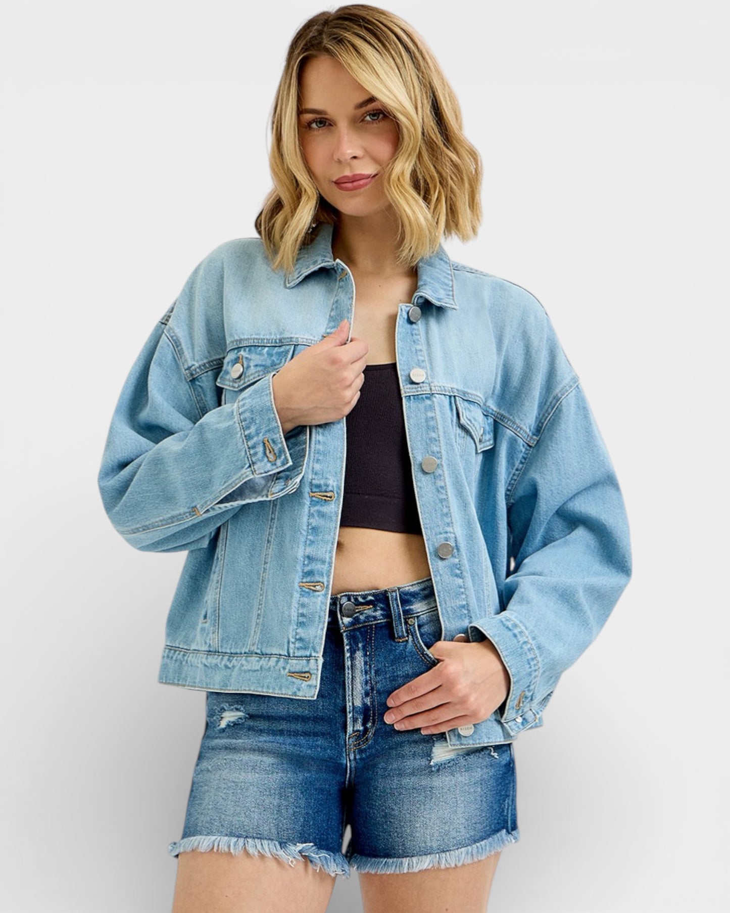 Woman wearing a light blue denim jacket and shorts on a white background