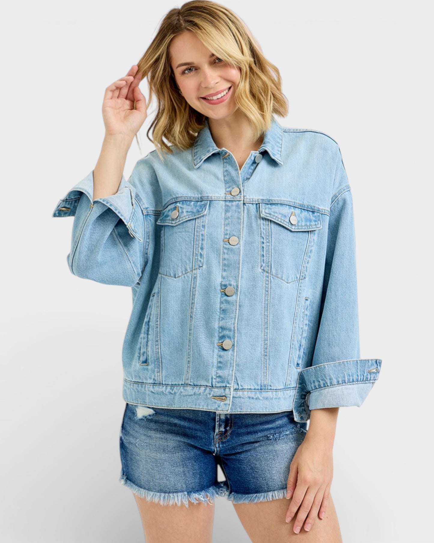Woman wearing a light blue denim jacket and shorts on a white background