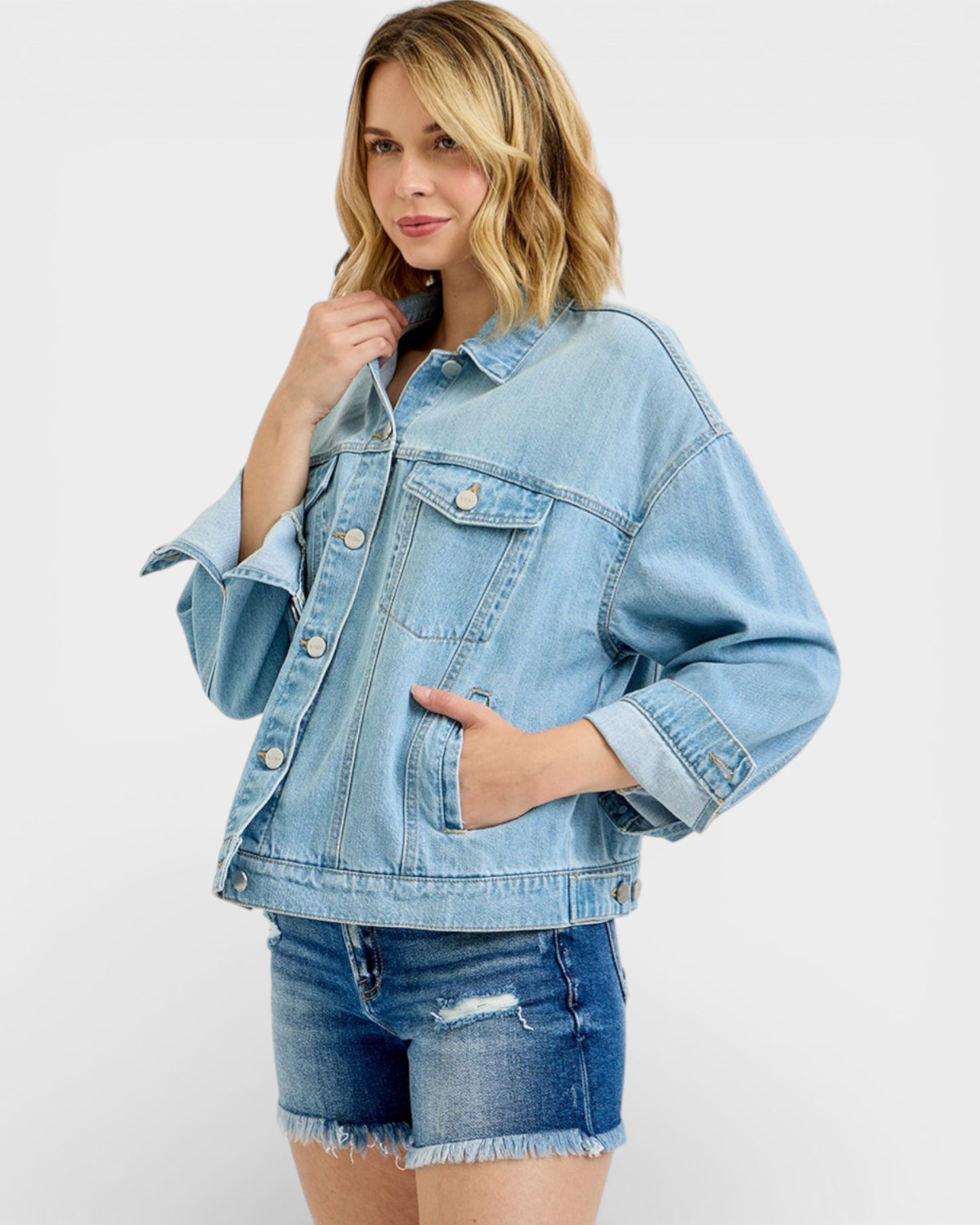 Woman wearing a light blue denim jacket and shorts on a white background