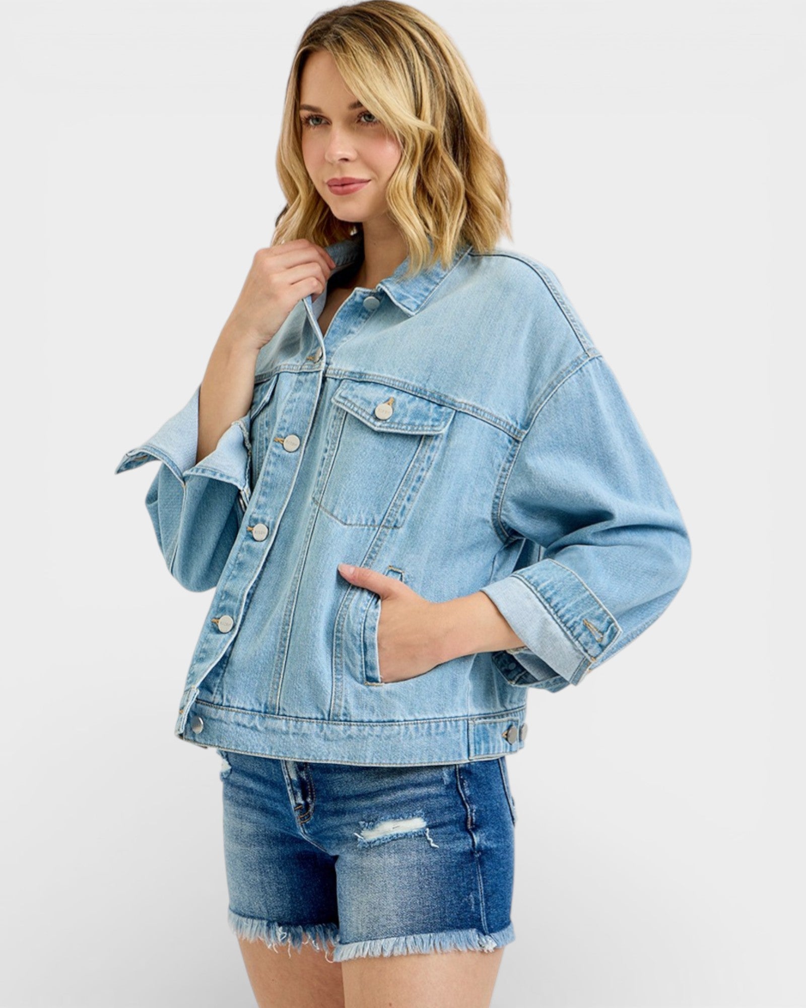 Woman wearing a light blue denim jacket and shorts on a white background