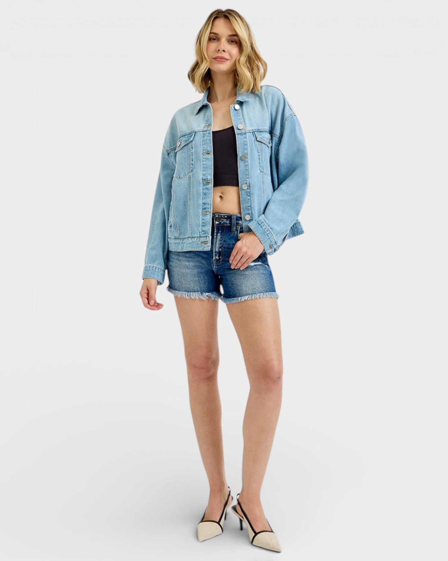 Woman wearing a denim jacket and shorts on a white background