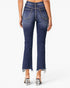Rear view of a model wearing dark blue denim flare jeans with a frayed hem and clear block-heel sandals against a light gray studio background.
