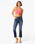 A woman modeling a pink ribbed crop top and dark blue high-waisted cropped jeans with frayed hems, paired with clear high-heeled sandals, against a plain white studio background.