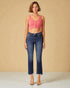 Woman wearing a pink top and blue jeans against a beige background