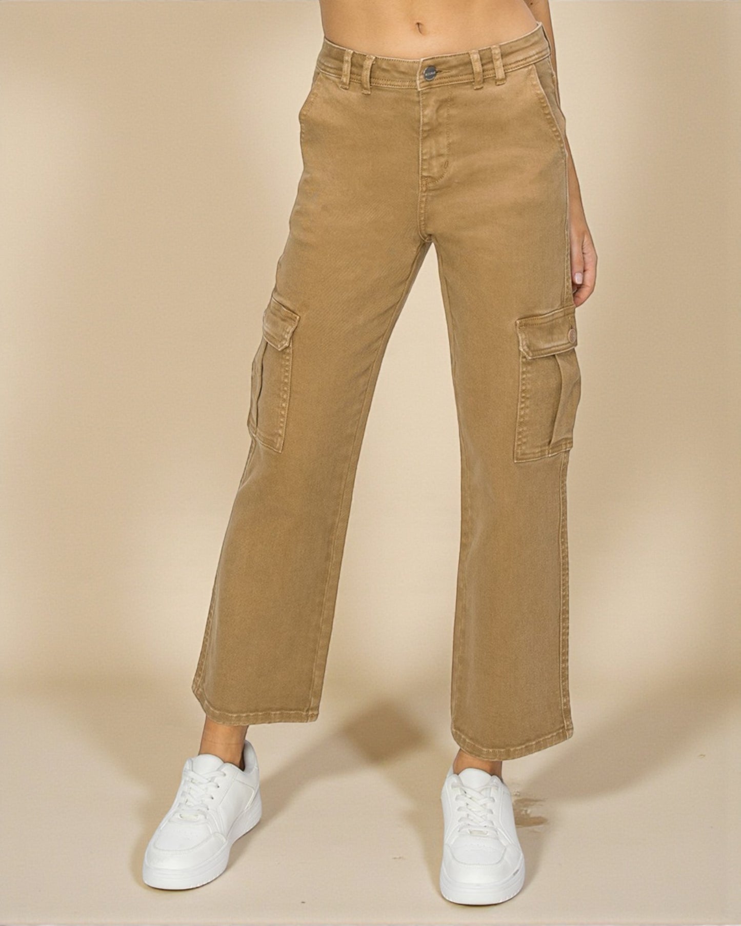 Person wearing tan cargo pants and white sneakers on a beige background