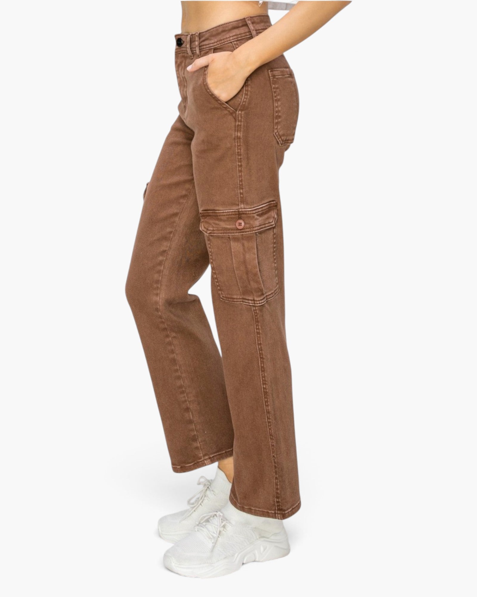A person wearing brown wide-leg cargo jeans with side flap pockets, paired with white sneakers, shown from the waist down against a plain light background.