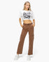 A model wearing a white cropped graphic t-shirt and brown wide-leg cargo pants, standing against a light gray studio background.