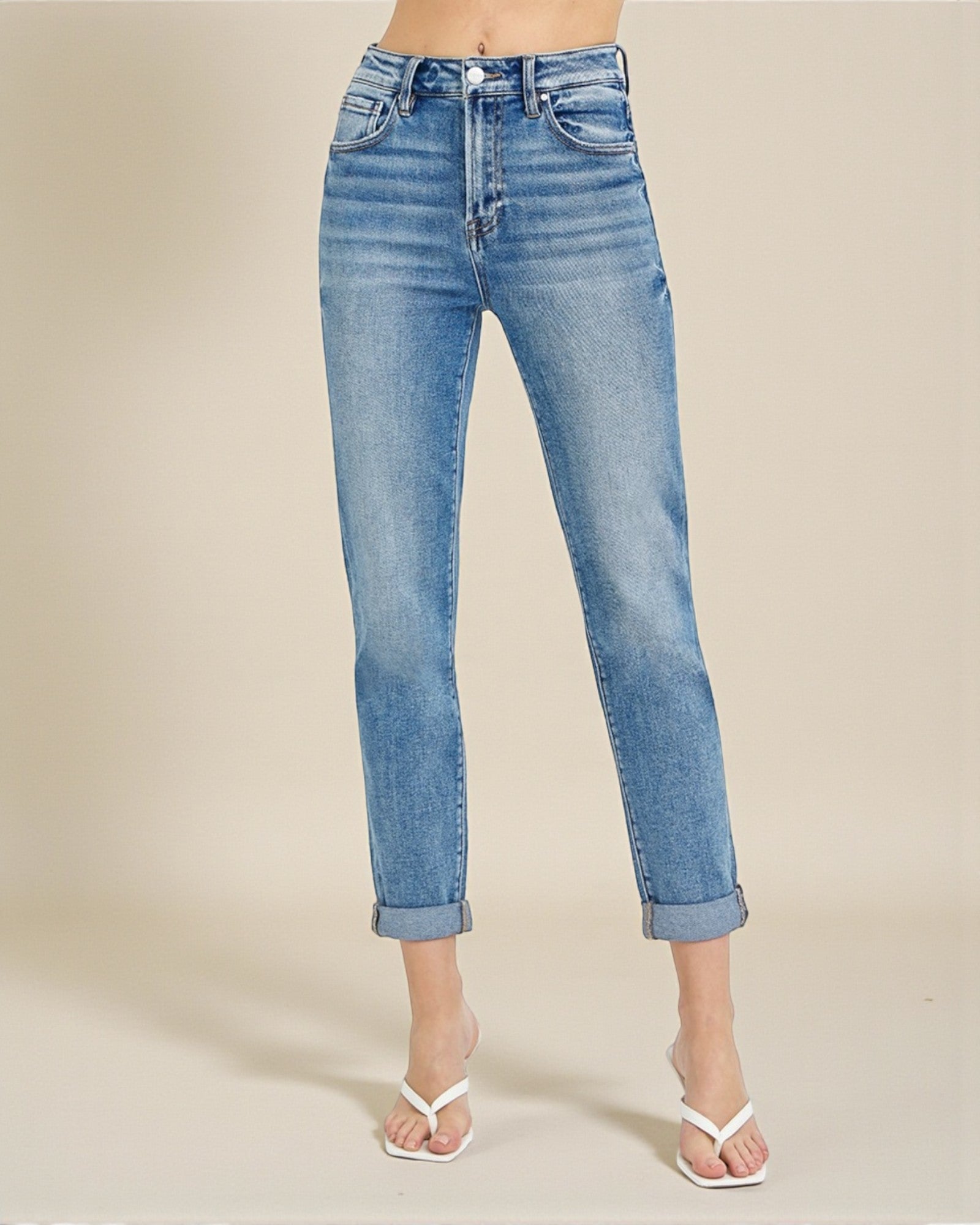 Blue jeans worn by a person on a beige background
