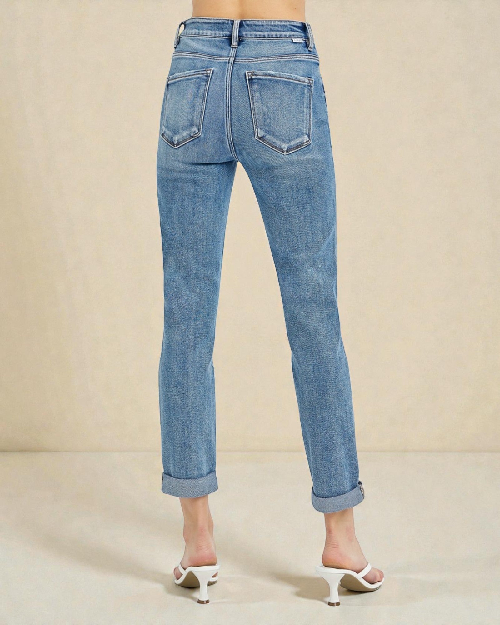 Blue jeans worn by a person on a beige background