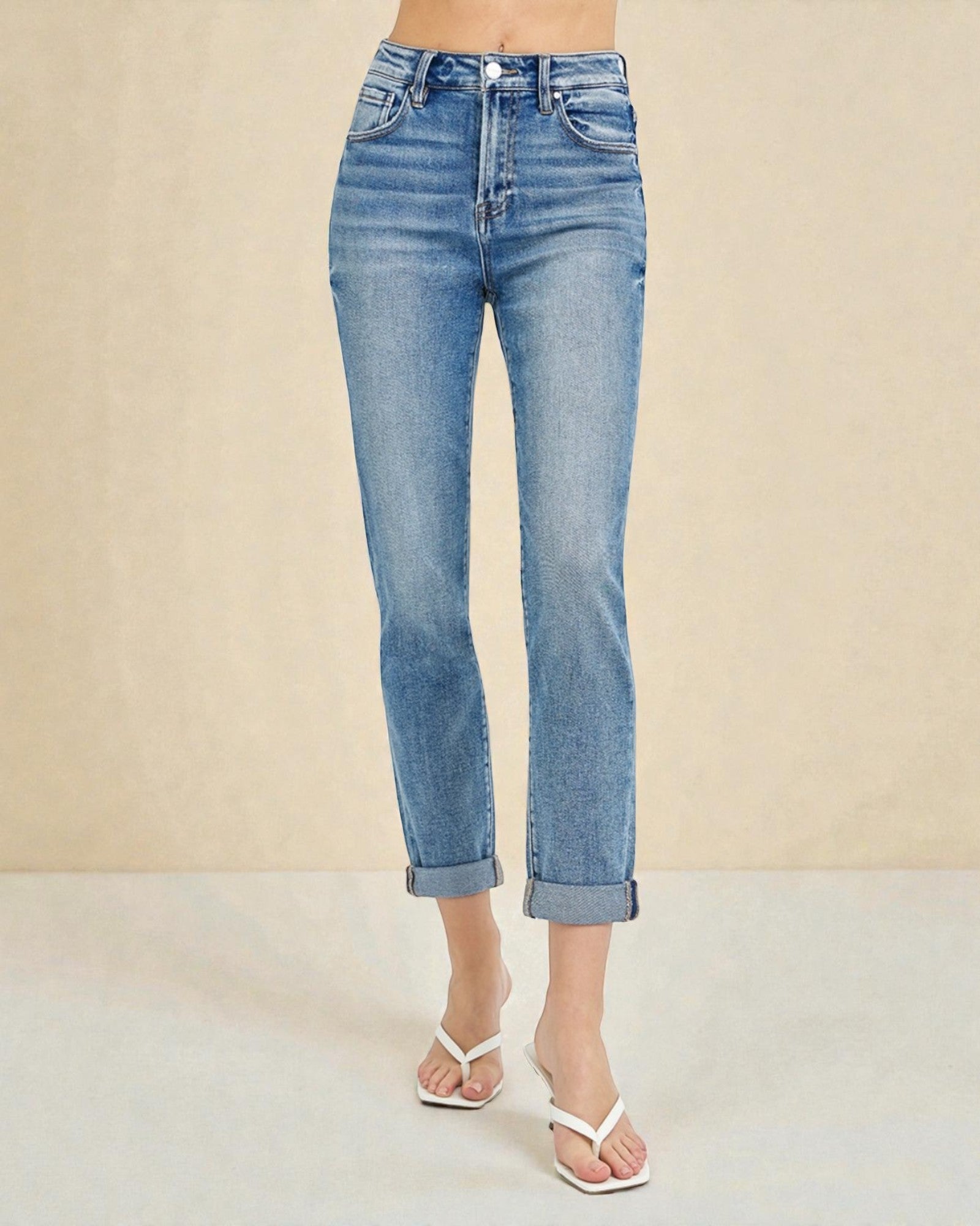 Blue jeans worn by a person on a beige background