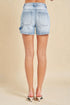 Light blue denim shorts worn by a person on a beige background