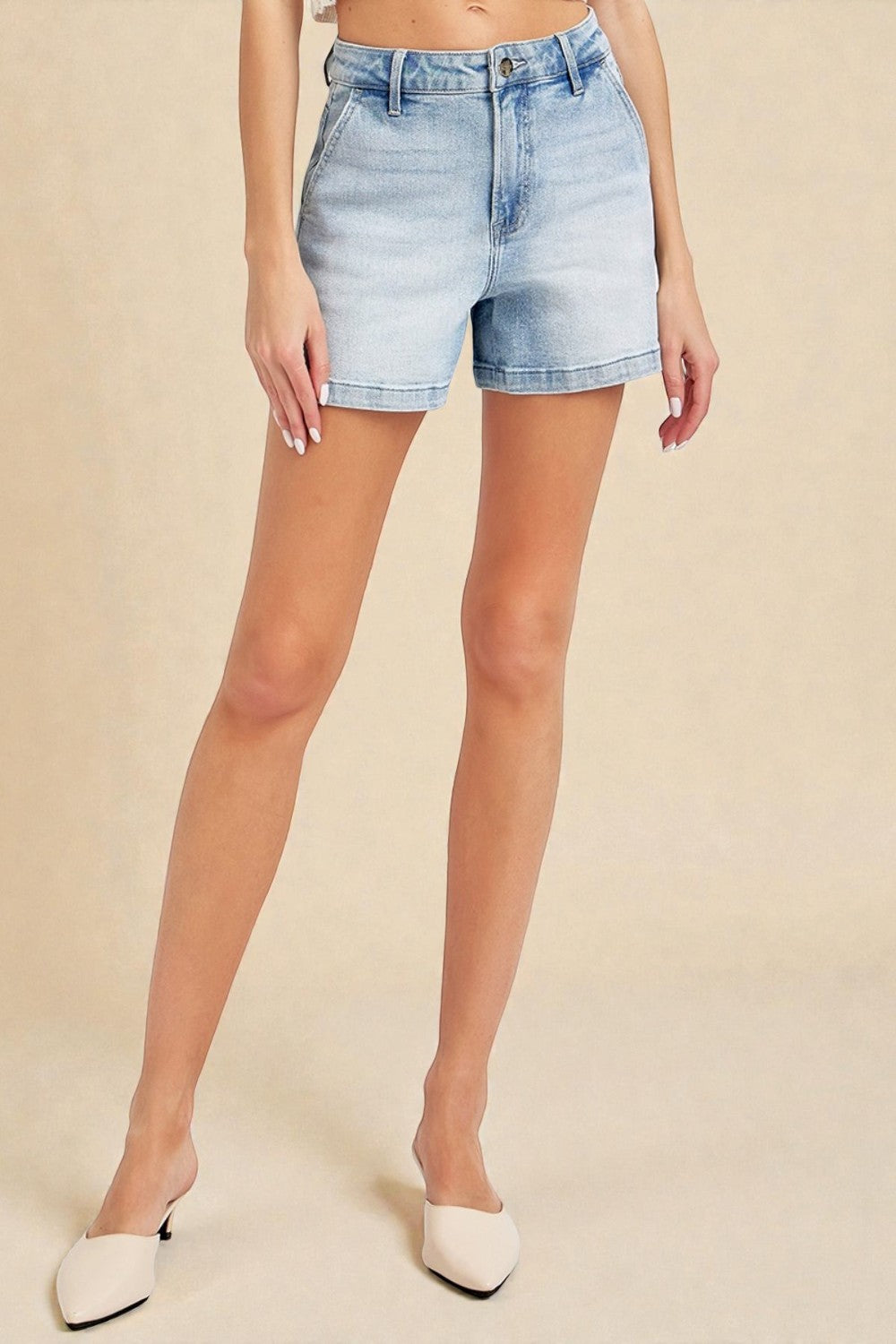 Person wearing light blue denim shorts on a beige background