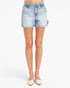 Light-wash blue denim shorts with a faded wash, modeled on a person wearing beige pointed-toe flats against a plain white studio background.