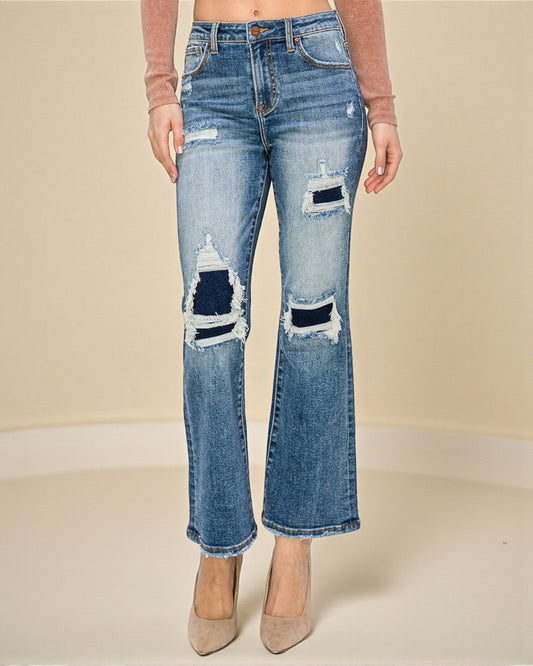 Distressed blue jeans worn by a person on a beige background