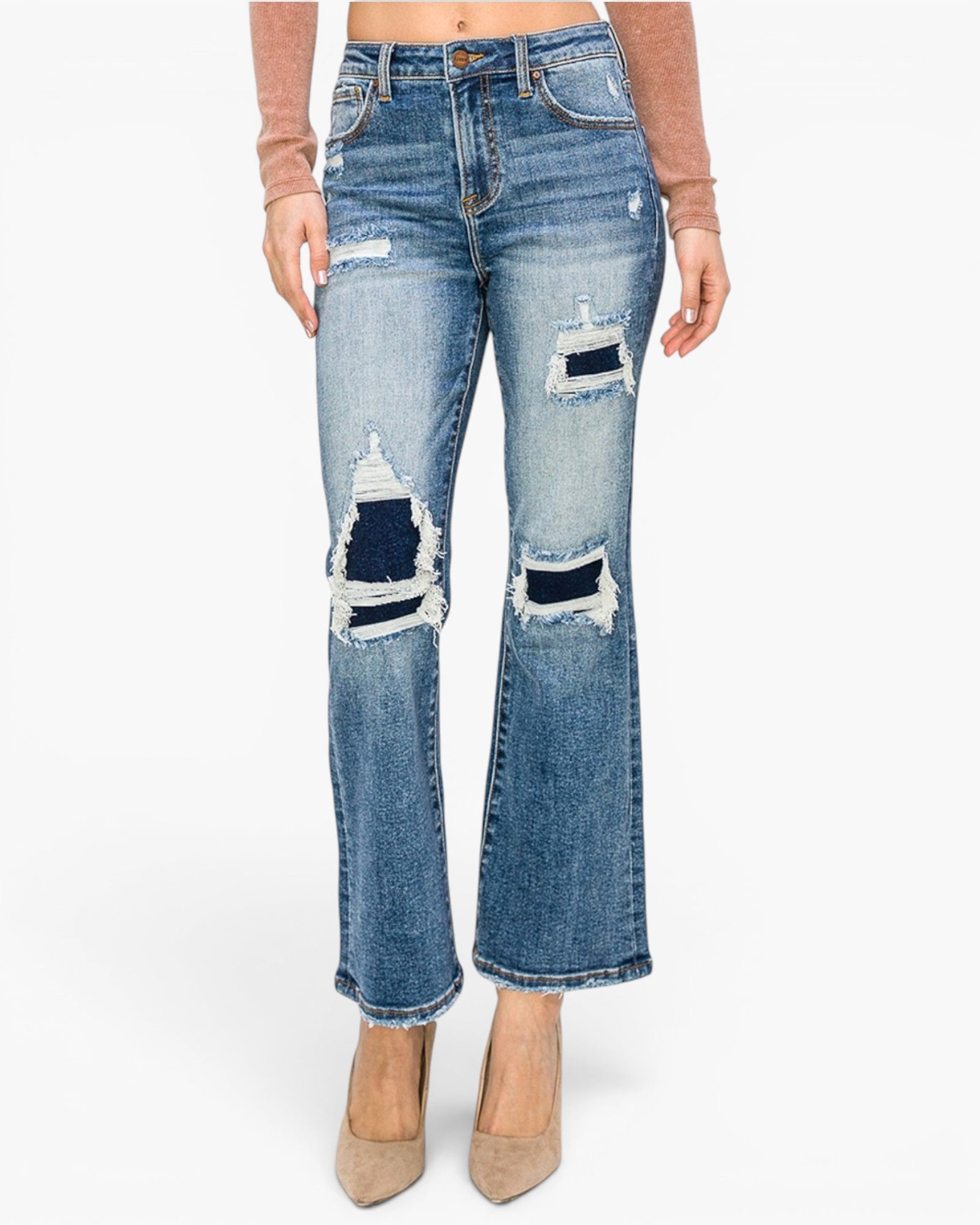 A person wearing medium-wash blue distressed flare jeans with ripped details and frayed edges, paired with beige pointed-toe heels and a brown long-sleeve top, shown against a plain light gray studio background.