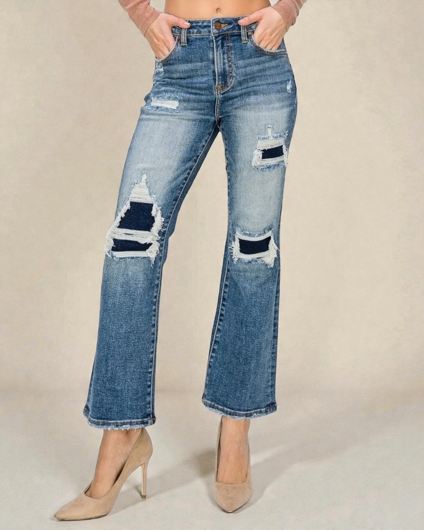 Distressed blue jeans worn by a person on a beige background