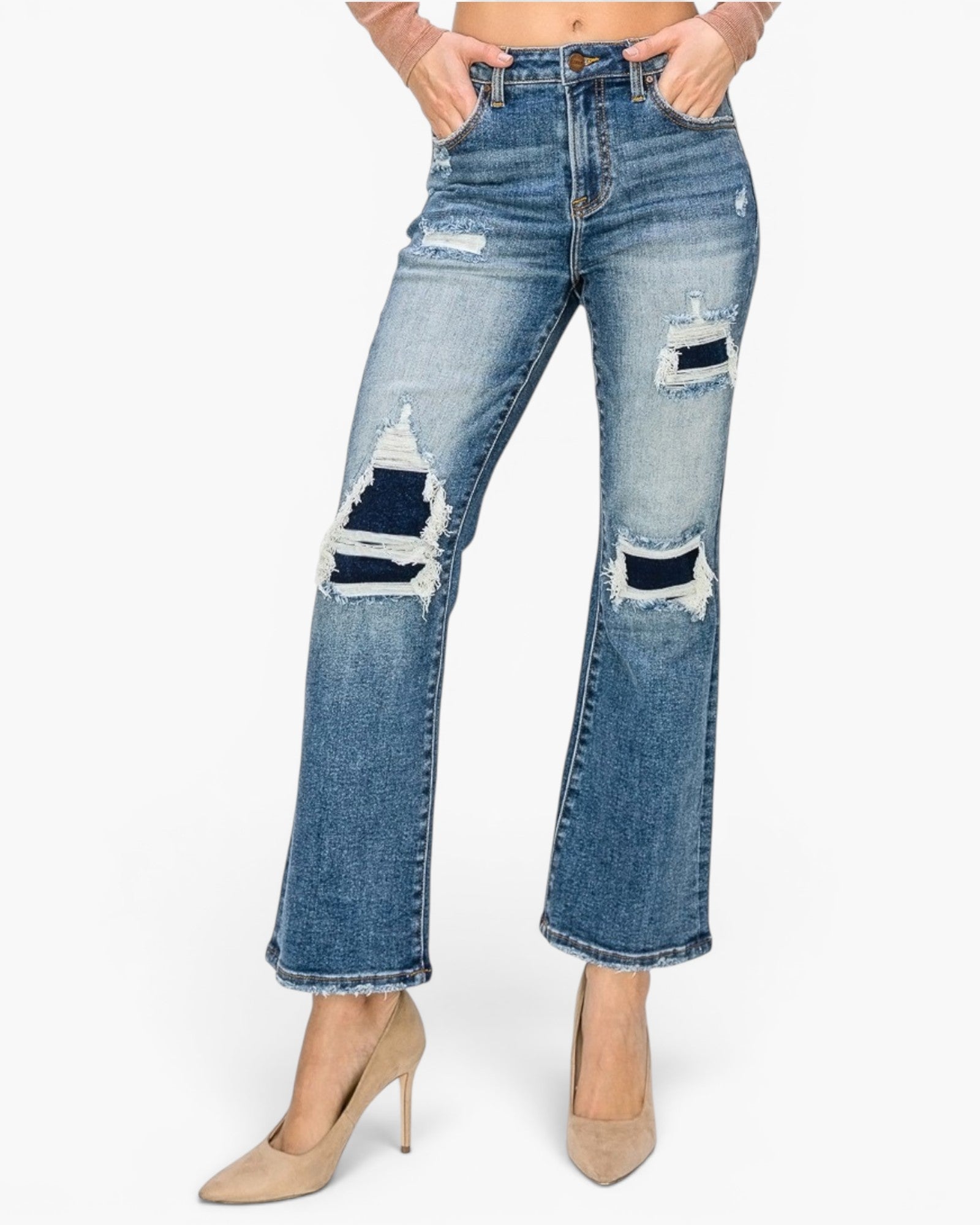 A model wearing a pair of medium-wash blue denim jeans with distressed rips on the thighs and knees, paired with beige high heels against a plain white background.