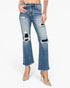 A model wearing a pair of medium-wash blue distressed flare jeans with ripped details on the thighs and knees, paired with beige high heels and a beige long-sleeve top against a plain white background.