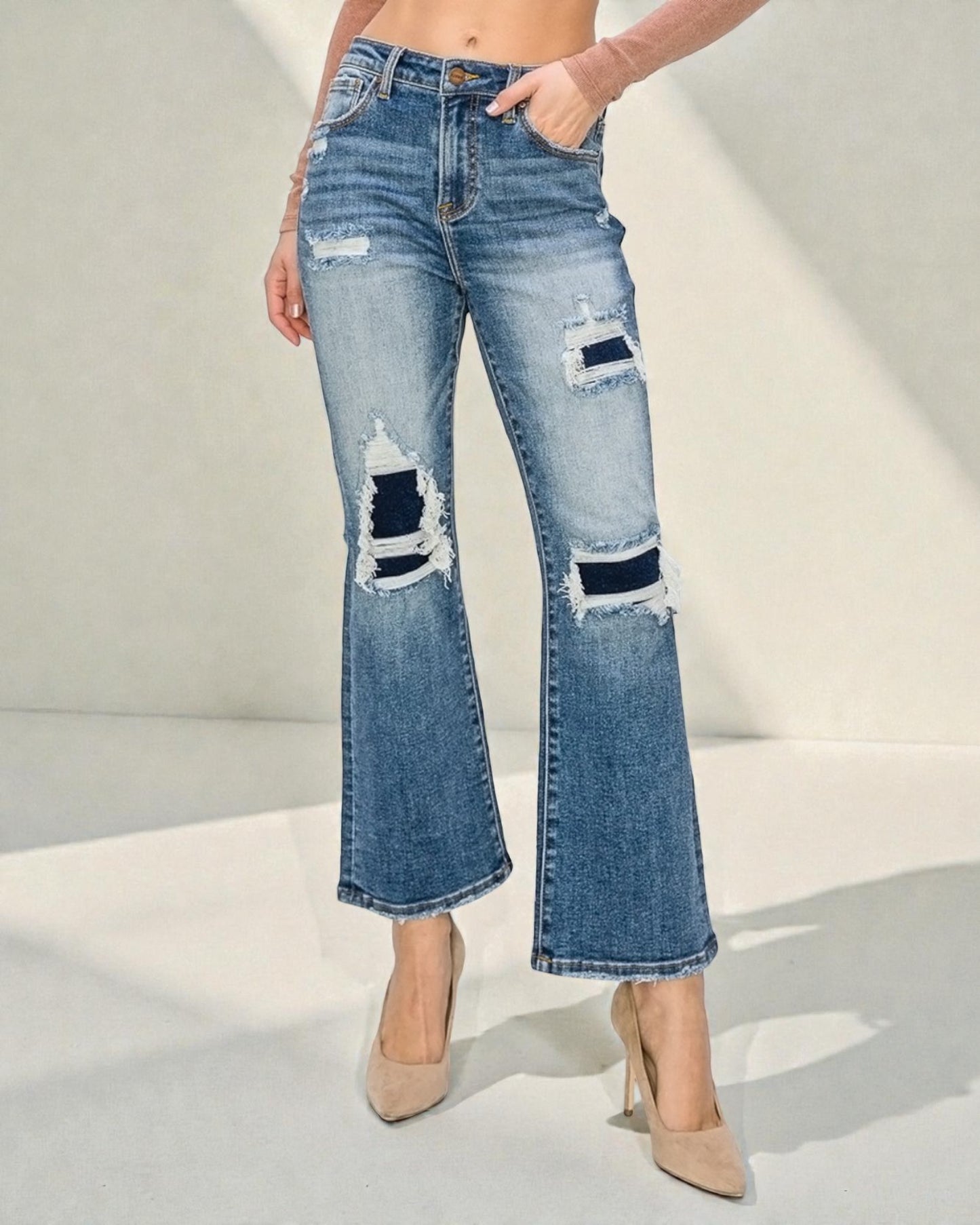 Distressed blue jeans worn by a person on a light gray background