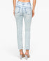 Back view of a model wearing light-wash blue denim jeans with a raw hem and clear-strap high-heeled sandals against a white studio background.
