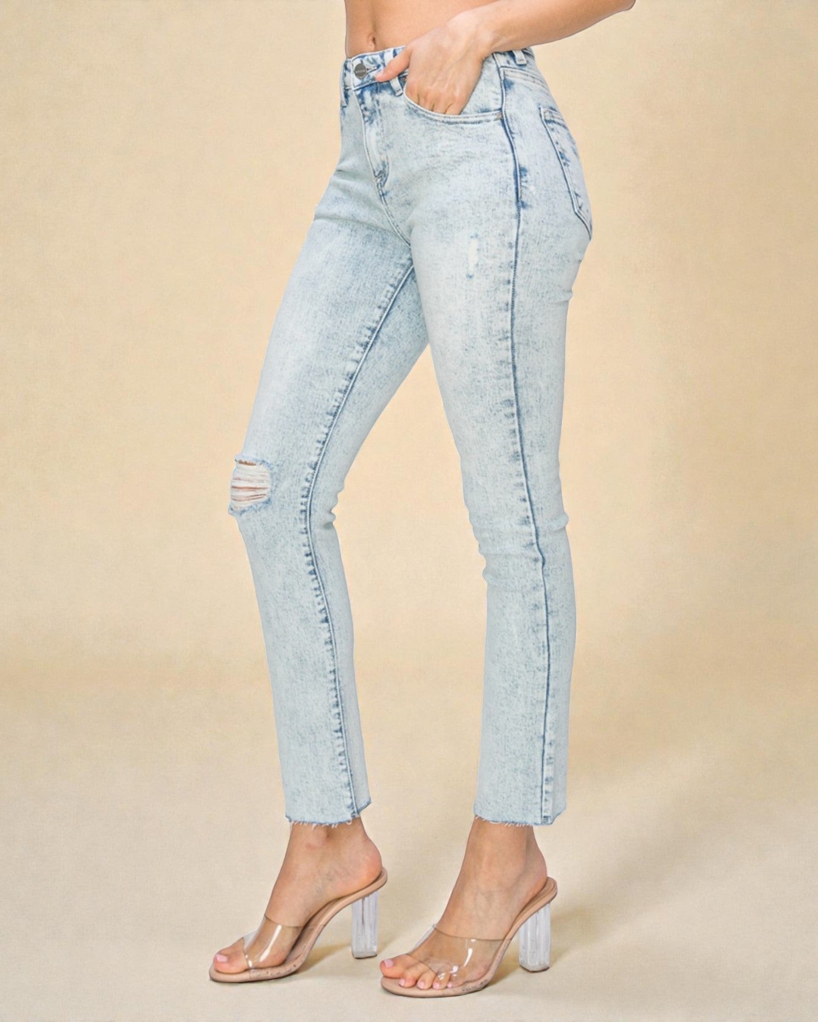 Light blue distressed jeans worn by a person on a beige background