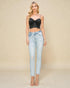 Woman wearing a black top and light blue jeans on a beige background