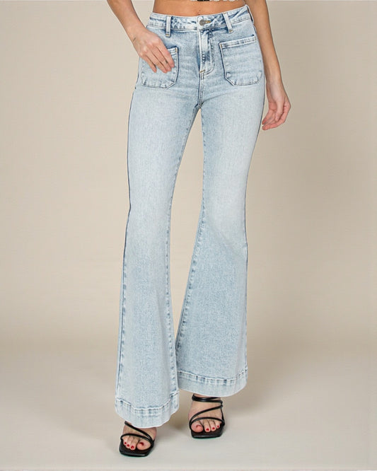 Light blue flared jeans worn by a person on a beige background