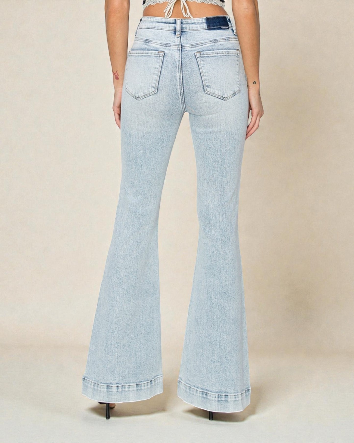 Light blue flared jeans worn by a person on a beige background