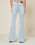 Light blue flared jeans worn by a person on a beige background