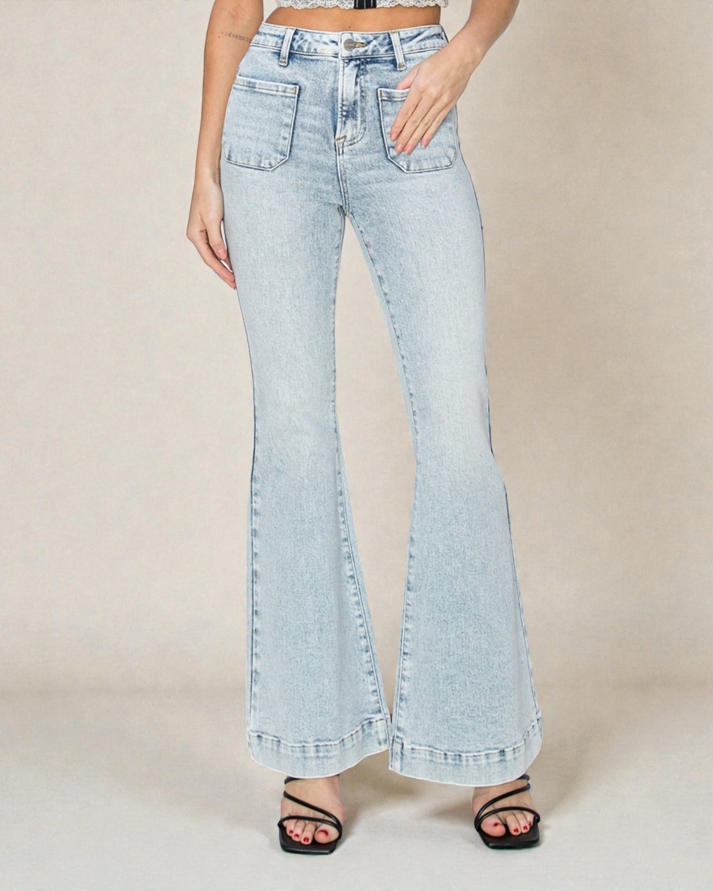 Light blue flared jeans worn by a person on a beige background