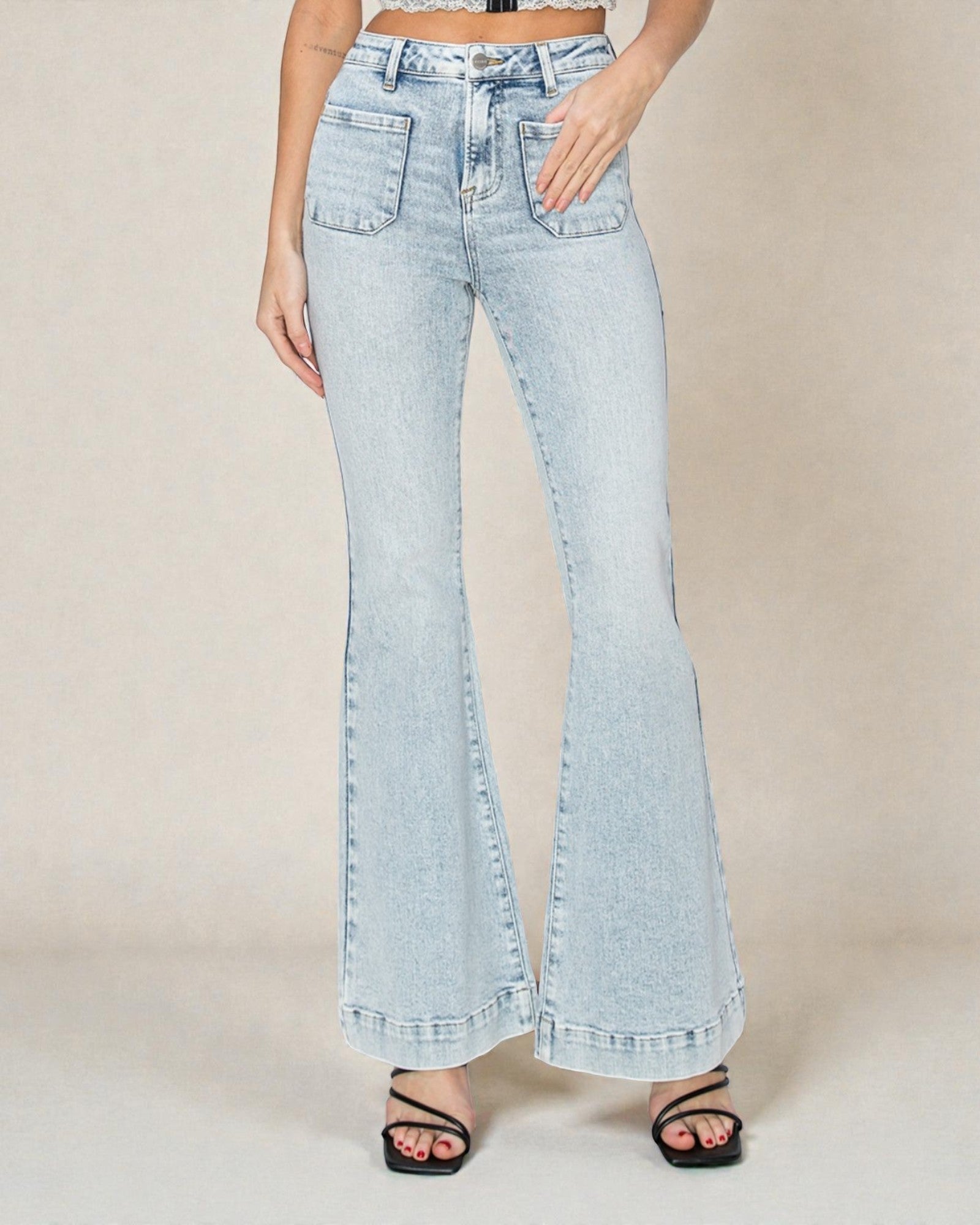 Light blue flared jeans worn by a person on a beige background