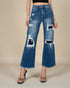 Distressed blue jeans worn by a person on a beige background