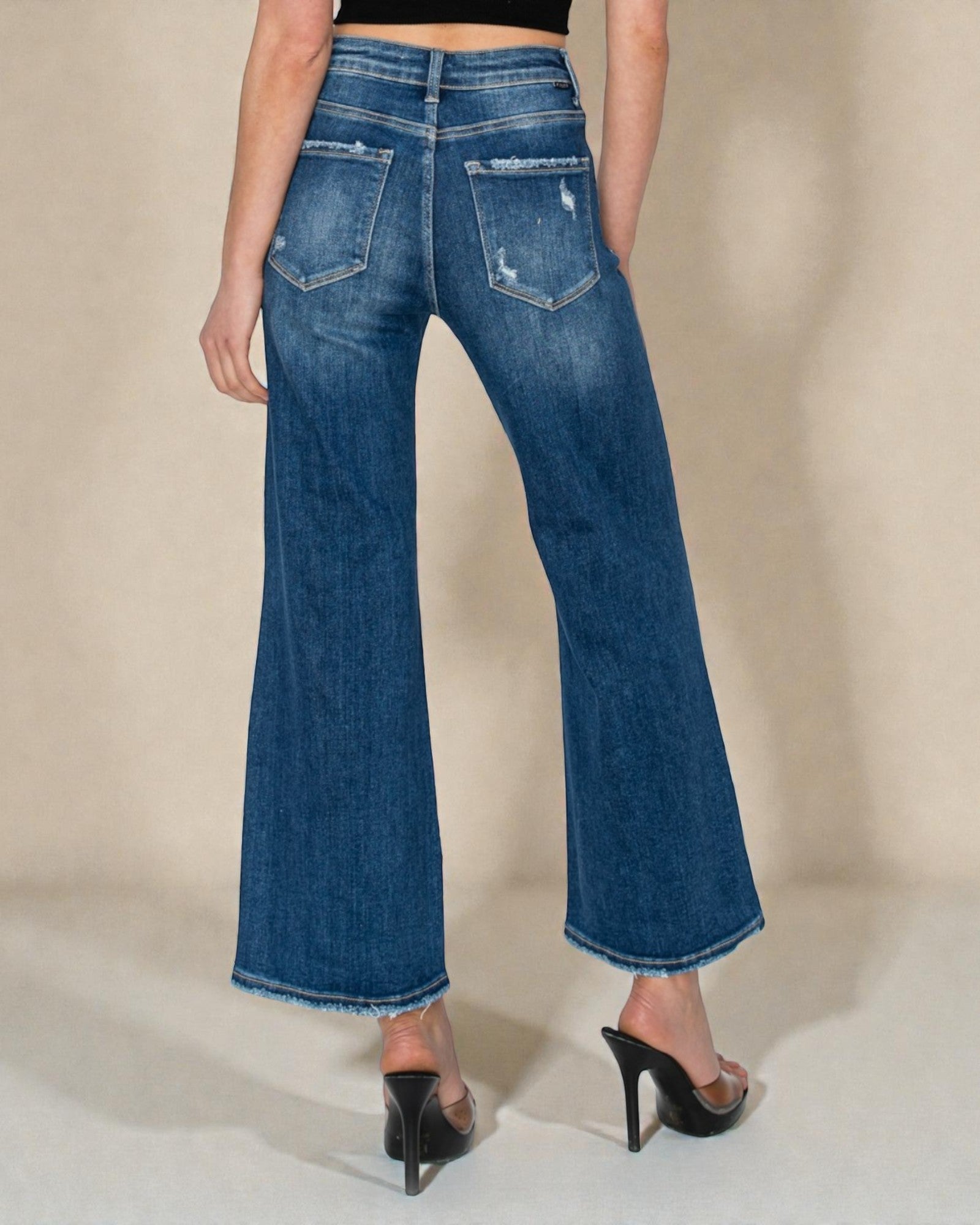 Person wearing blue flared jeans on a neutral background