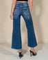 Person wearing blue flared jeans on a neutral background