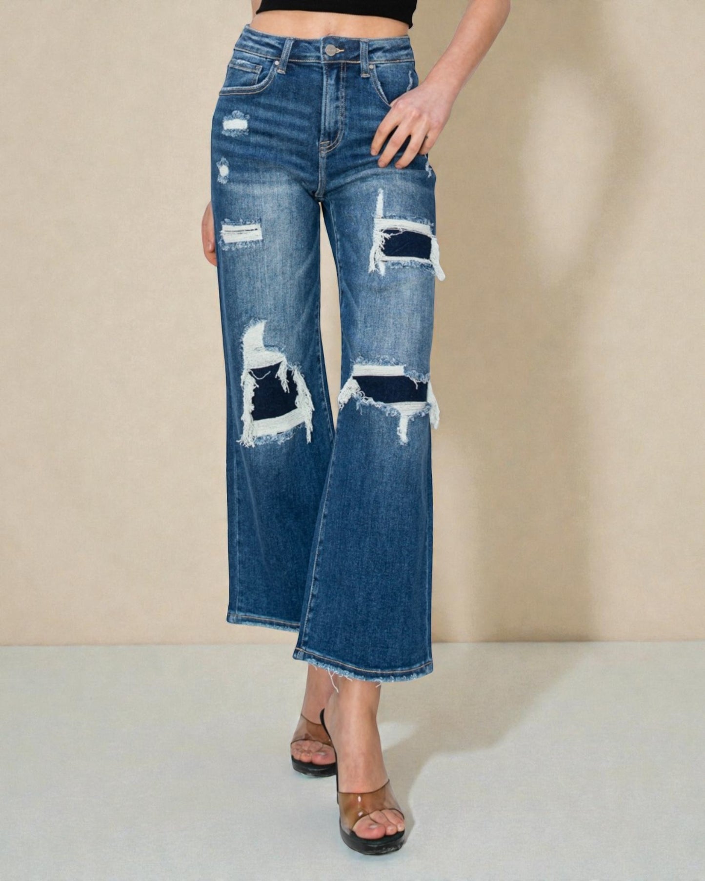 Distressed blue jeans worn by a person on a beige background