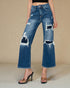 Person wearing distressed blue jeans on a beige background