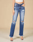 Person wearing distressed blue jeans on a beige background