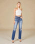 Woman wearing a white halter top and distressed blue jeans on a beige background