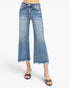 A model wearing light blue cropped flare jeans with a frayed hem and distressed details, paired with leopard-print flat sandals, against a plain white background.