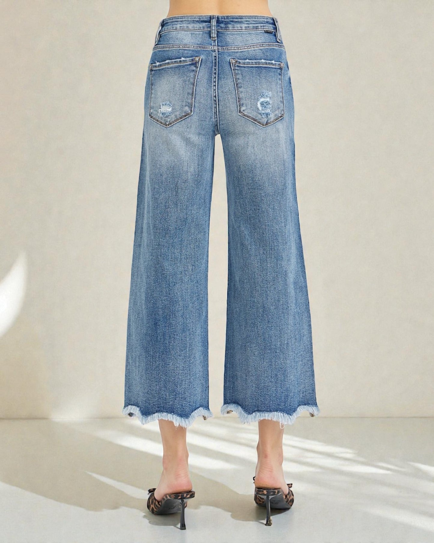 Blue denim wide-leg jeans worn by a person on a white background