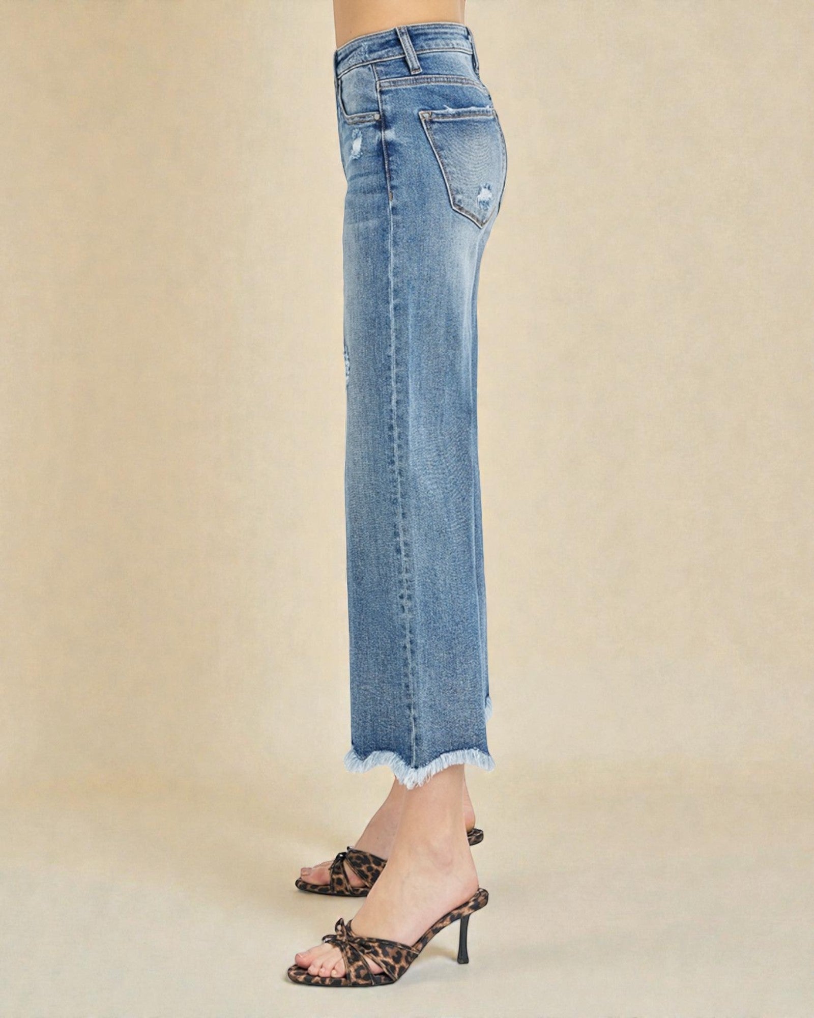 Light blue jeans with a frayed hem on a beige background
