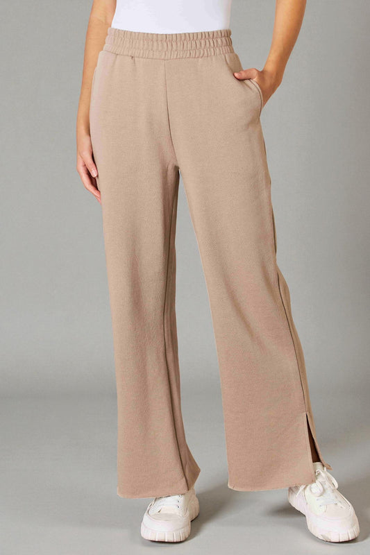Beige wide-leg pants worn by a person on a gray background