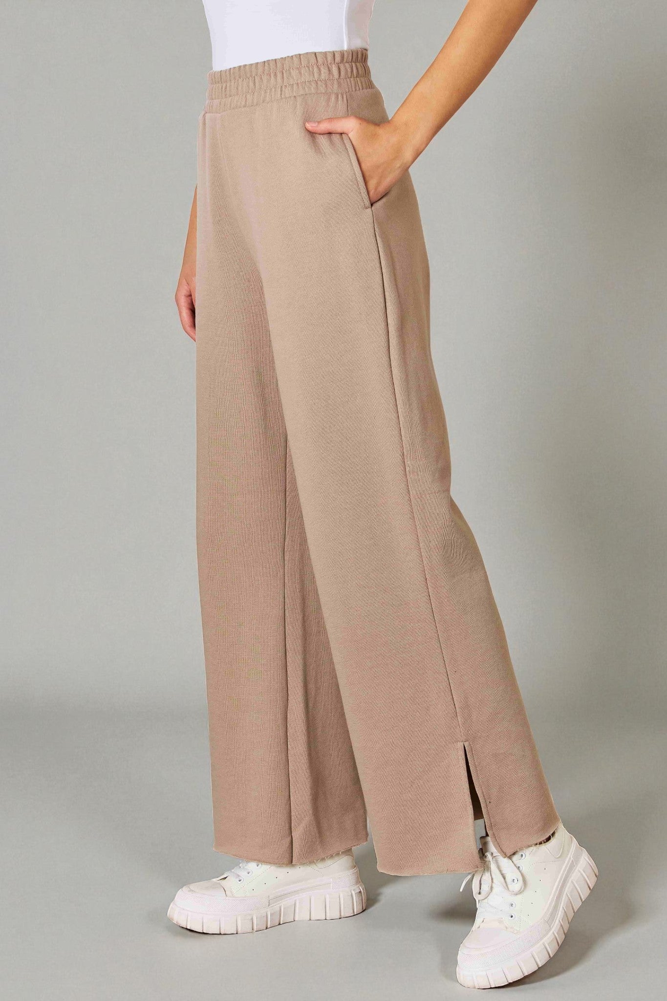 Beige wide-leg pants worn by a person on a gray background