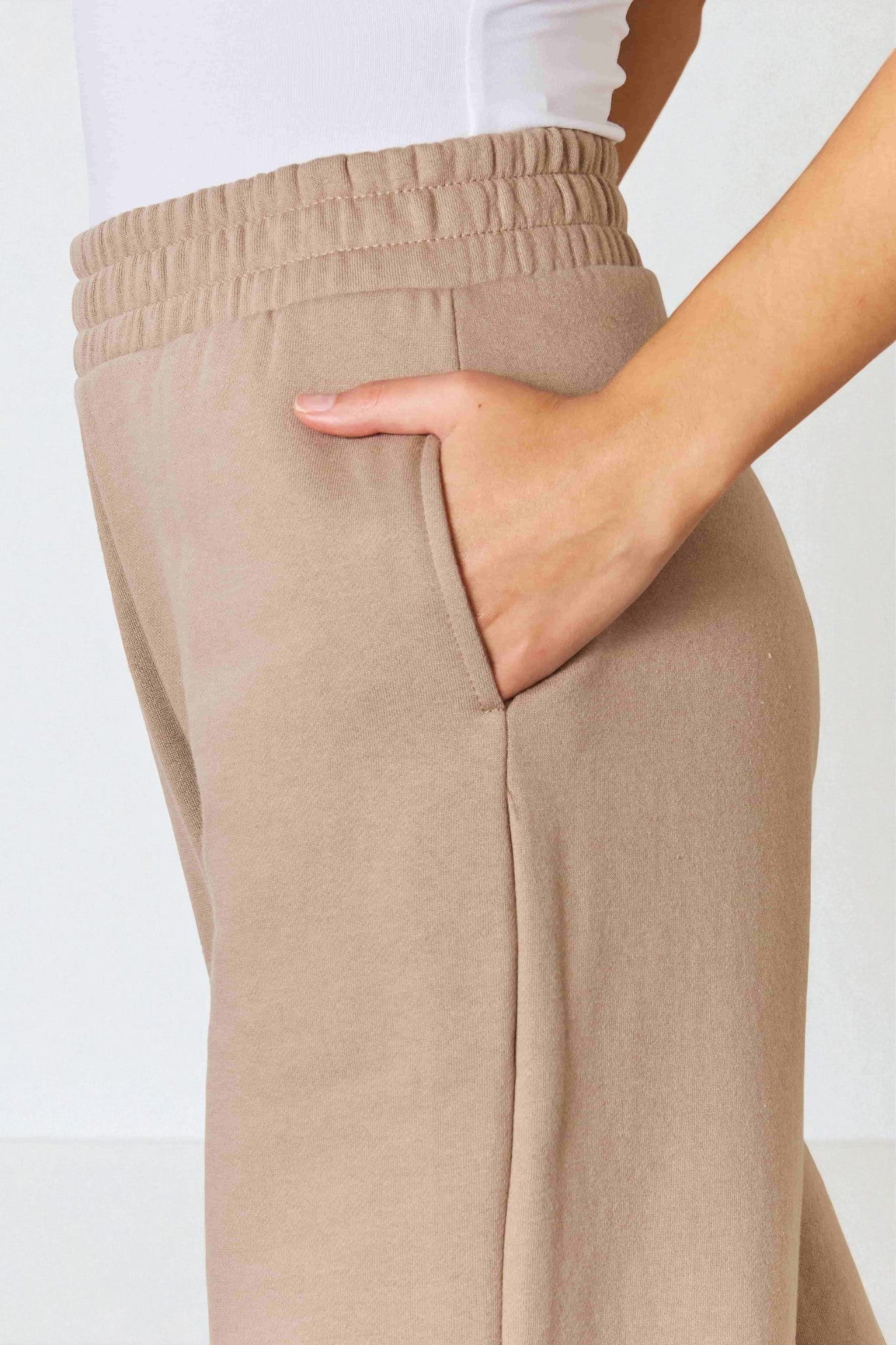 Beige pants worn by a person on a white background
