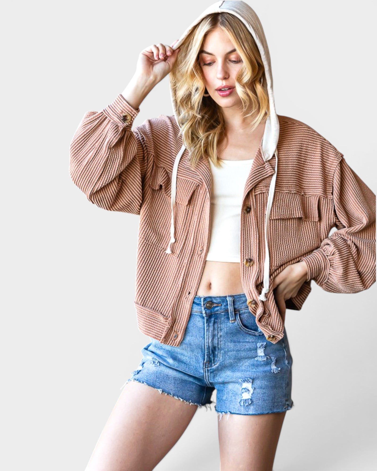 Woman wearing a brown ribbed hoodie and denim shorts on a white background