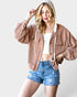 Woman wearing a brown ribbed hoodie and denim shorts on a white background