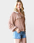 Woman wearing a brown ribbed knit cardigan and denim shorts on a white background