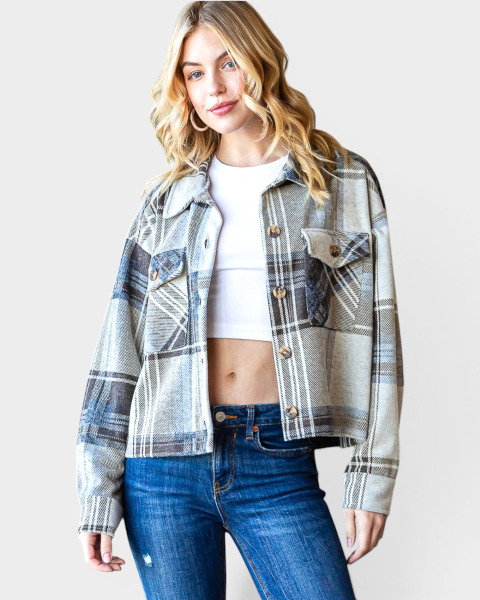 Woman wearing a plaid jacket and jeans on a plain background