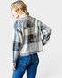 Person wearing a plaid shirt and blue jeans on a plain background