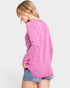 Woman wearing a pink sweater and denim shorts on a light gray background